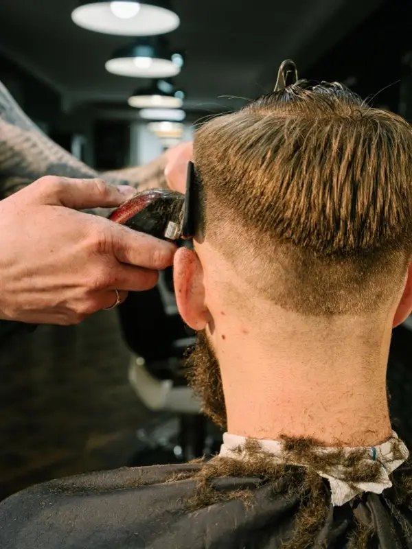 A barber working a fade with clippers in a barbershop