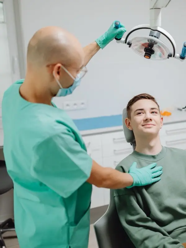 A dentist adjusting the lamp over a smiling patient in the chair